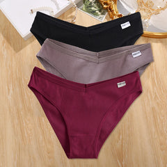 Three pairs of ribbed underwear in black, gray, and burgundy on a wooden surface.
