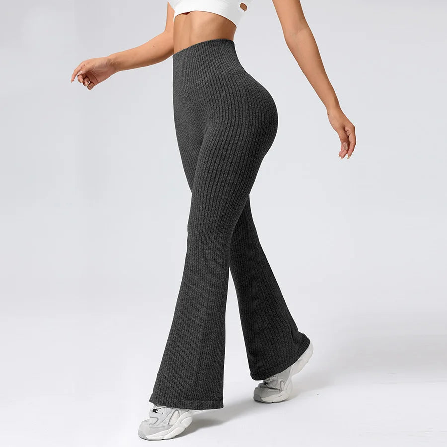 Person wearing dark ribbed knit pants on a white background