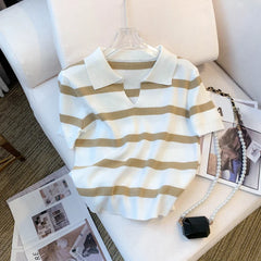 Striped shirt on a hanger with a black handbag and photo album on a white surface.