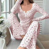 Woman wearing a pink floral pajama set sitting on a couch with flowers in the foreground.