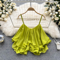 Green ruffled top on a hanger with floral decorations in the background