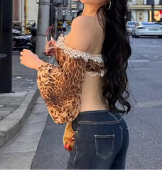 Woman wearing a leopard print top and denim shorts on a city street.