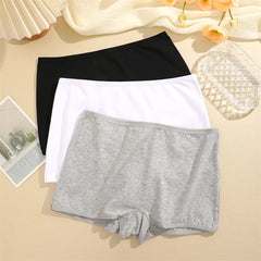 Three pairs of underwear in black, white, and gray on a beige surface.