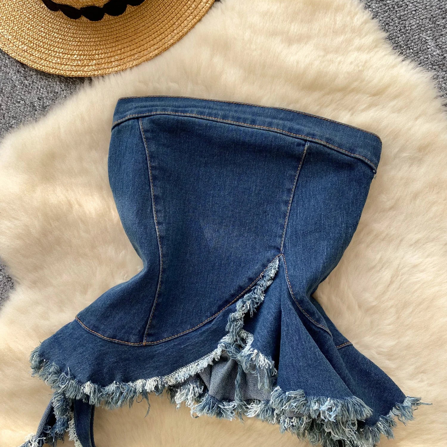 Blue denim skirt with fringe on a textured surface