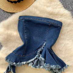 Blue denim skirt with fringe on a textured surface