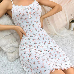 Woman wearing a white floral dress sitting on a fluffy white surface.