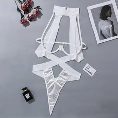 White lingerie set on a gray surface with flowers and a photo frame in the background.
