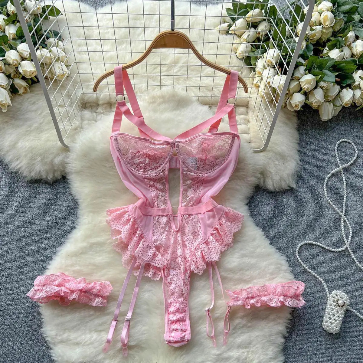 Pink lace lingerie set on a hanger with flowers in the background