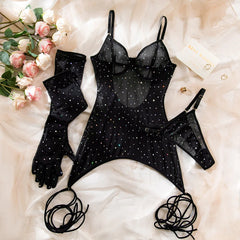 Black lingerie set with rhinestone details on a white surface with flowers and jewelry.