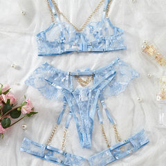 Blue lace lingerie set with chain details on a white background with flowers.