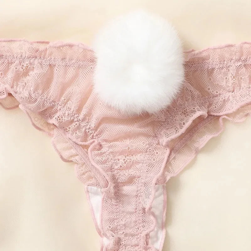 Pink lace thong with a white fluffy pom-pom on a beige background