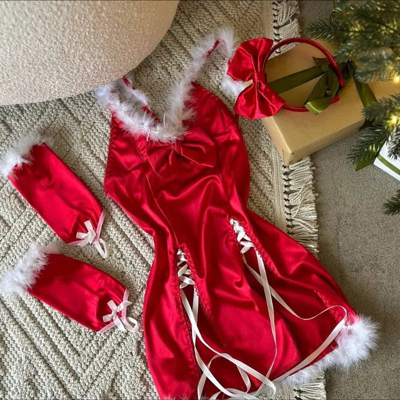 Red satin lingerie set with white fur trim on a textured surface near a Christmas tree.