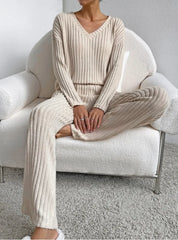 Person wearing a beige ribbed knit outfit sitting on a white chair.