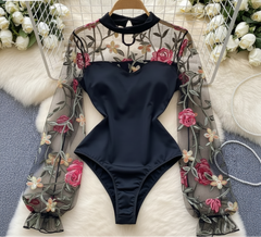 Black swimsuit with floral lace overlay on a white surface