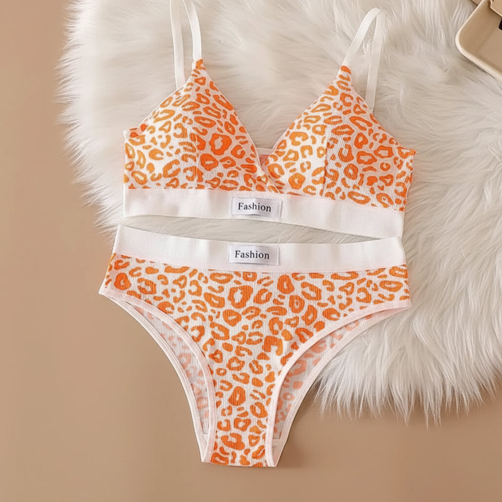 Orange leopard print bra and panties set on a beige surface with a fluffy white rug.