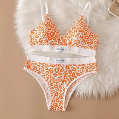 Orange leopard print bra and panties set on a beige surface with a fluffy white rug.