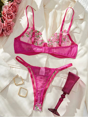 Pink lingerie set with floral embroidery on a white fabric background