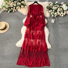 Red lace dress on a gray surface with flowers and a hat in the background