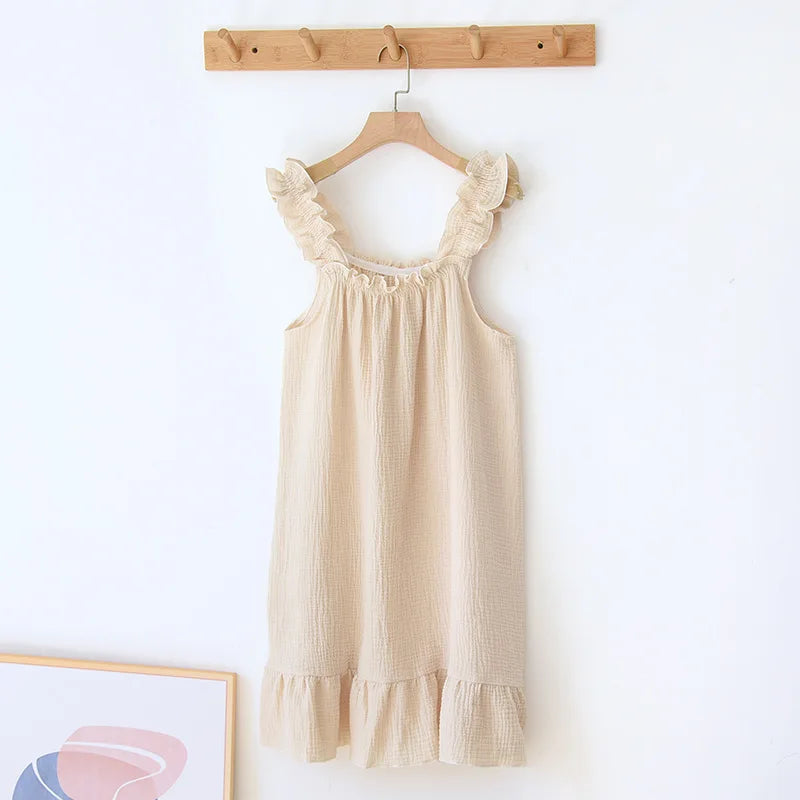 Beige dress with ruffled details hanging on a wooden hanger against a white wall.