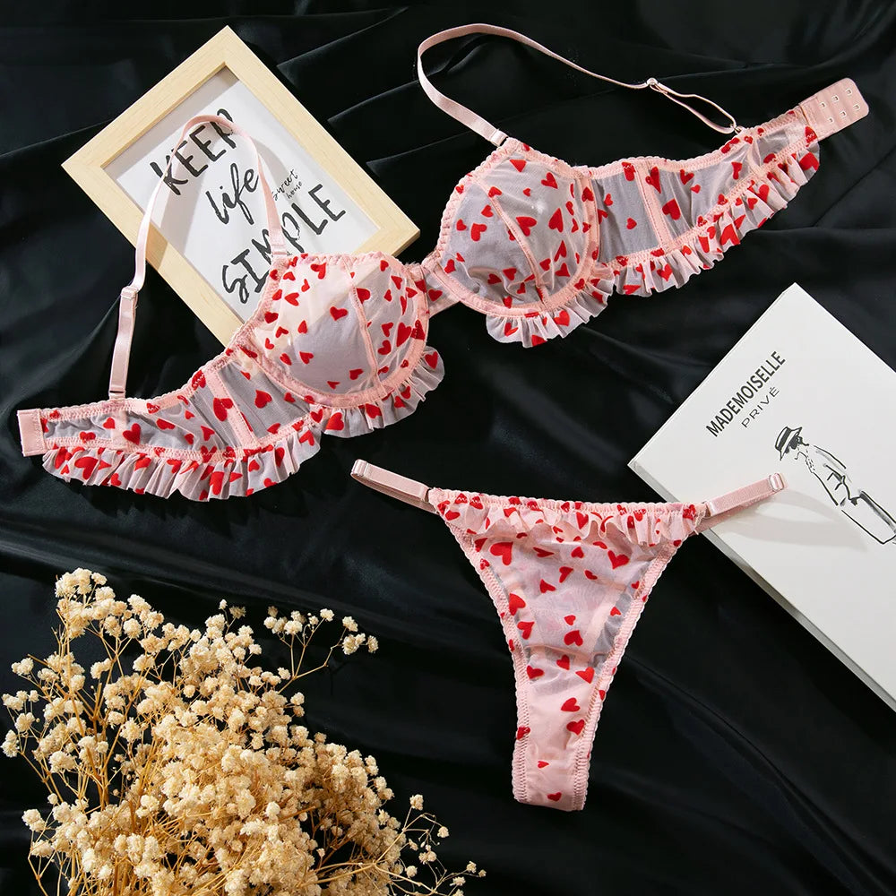 Heart-patterned lingerie set on a dark surface with decorative elements.