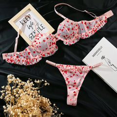Heart-patterned lingerie set on a dark surface with decorative elements.