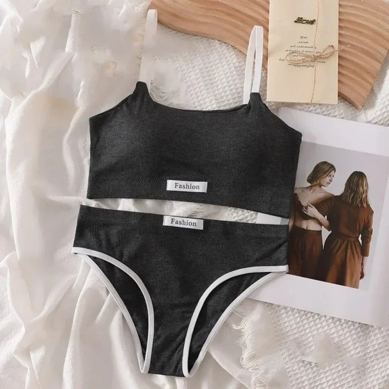 Black bikini set with 'Fashion' label on a textured surface with a magazine and photo in the background.