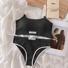 Black bikini set with 'Fashion' label on a textured surface with a magazine and photo in the background.