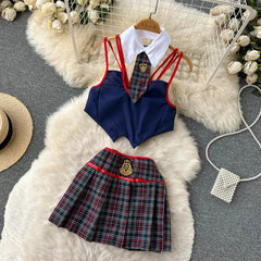 School uniform set with navy top, plaid skirt, and tie on a fluffy white rug.