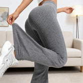 Person wearing gray ribbed pants and white sneakers in a living room setting