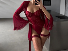 Person wearing a red lingerie set and robe in a modern kitchen.