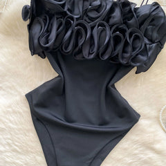 Black swimsuit with ruffled shoulders on a light background