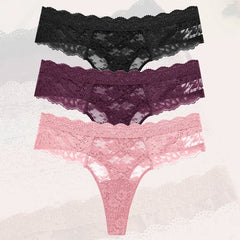 Three pairs of lace underwear in black, purple, and pink on a textured white background.