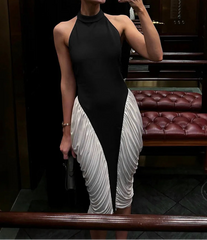 Woman taking a mirror selfie wearing a black and white dress in an indoor setting.