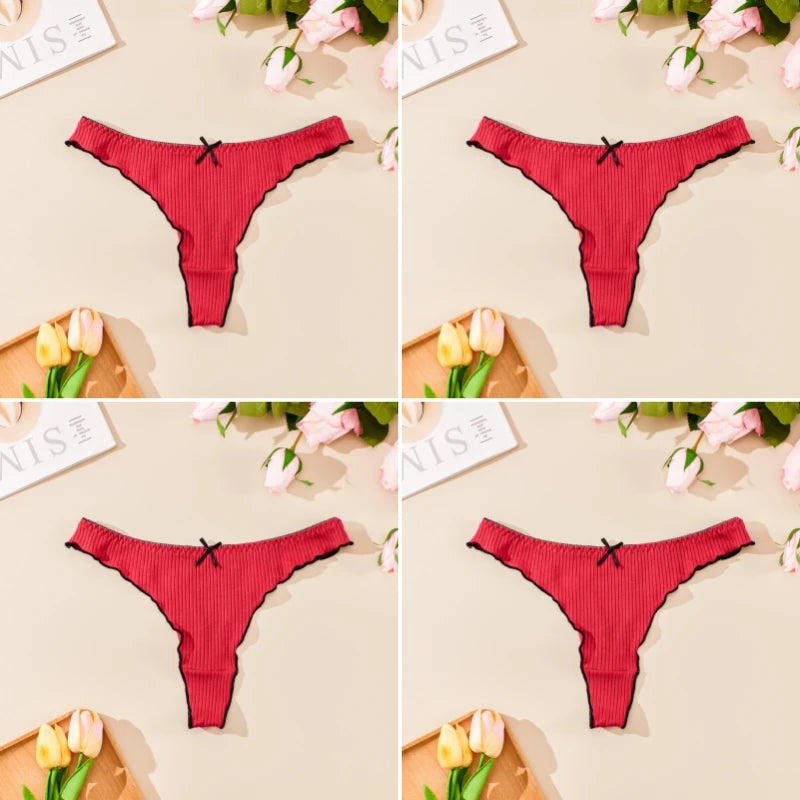 Red thong with a black bow on a beige background with flowers and magazines.