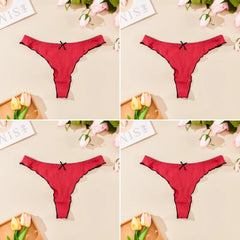 Red thong with a black bow on a beige background with flowers and magazines.
