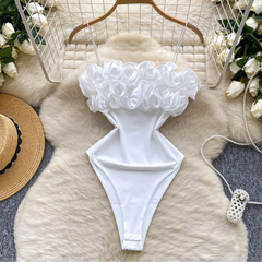 White bikini top with ruffled details on a fur surface with decorative elements.
