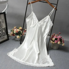 White satin slip dress on a hanger with flowers and a framed picture in the background.