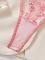 Close-up of a pink lace trim on a garment with floral embroidery.