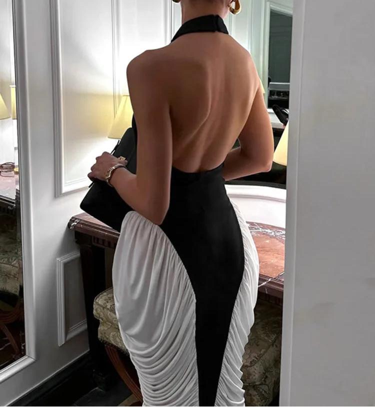 Woman in a black and white dress standing in front of a mirror.