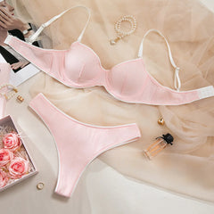Pink bra and panties set on a light background with flowers and jewelry.