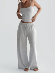 Woman wearing a gray tank top and wide-leg pants on a white background