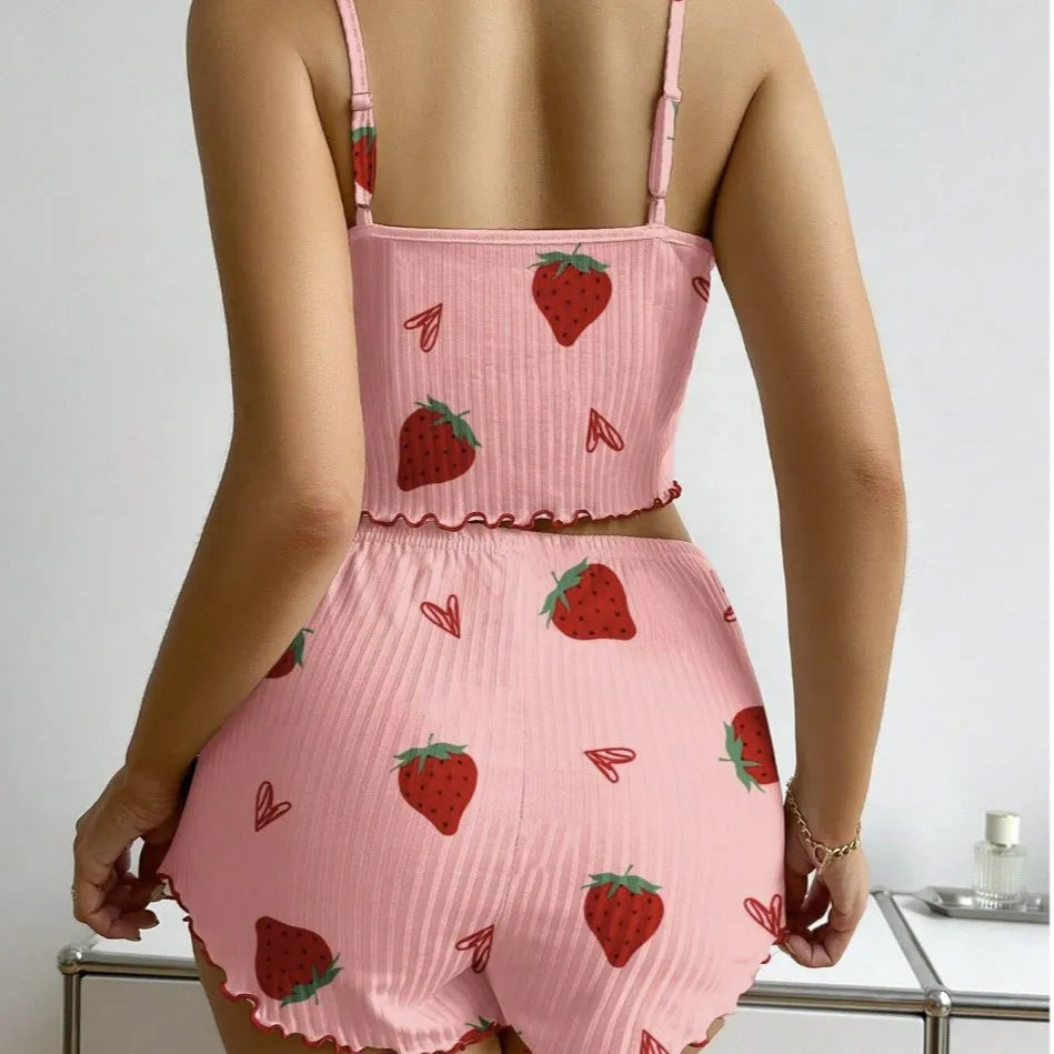 Pink romper with strawberry pattern worn by a person on a plain background