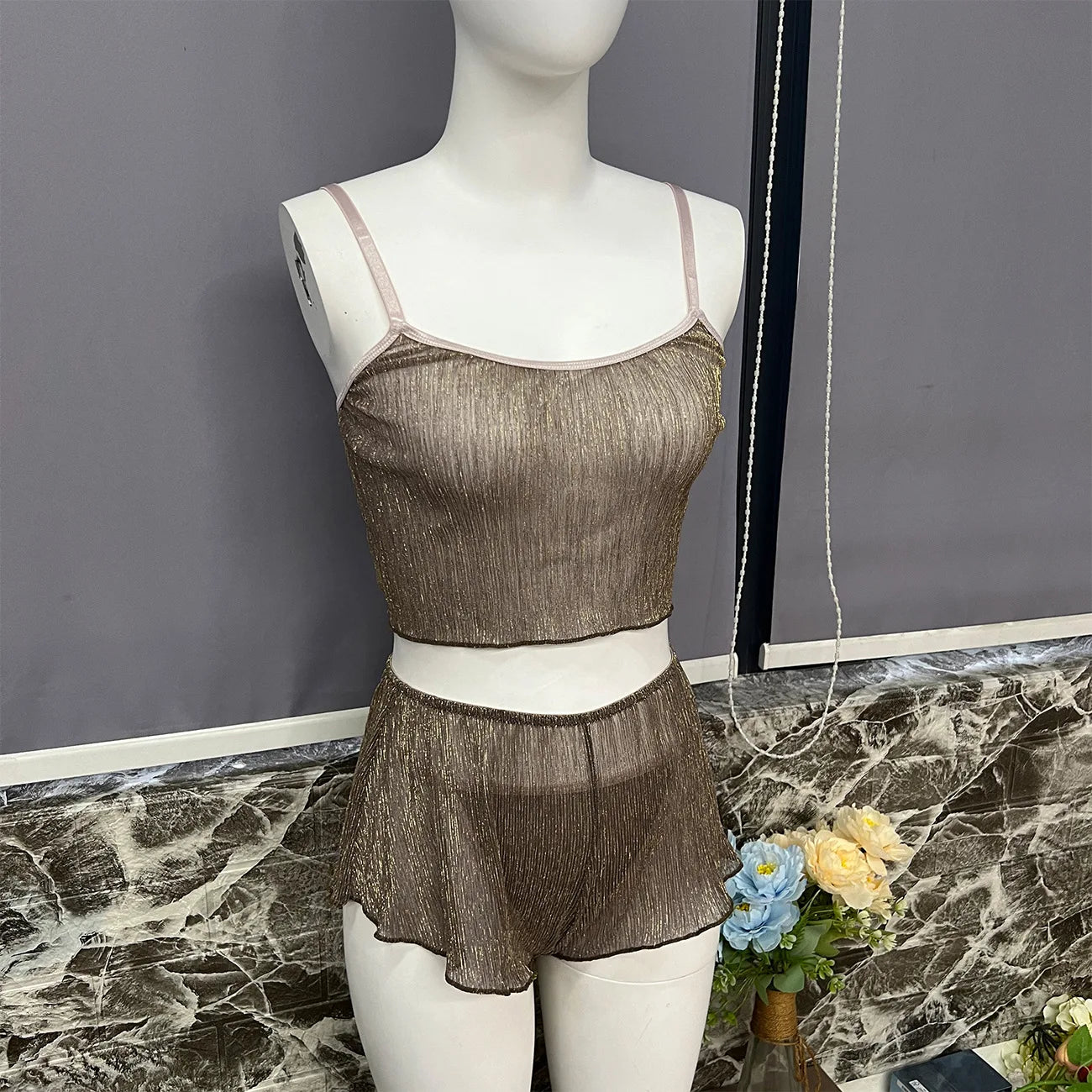 Mannequin wearing a brown lace lingerie set on a marble surface with a gray wall background.
