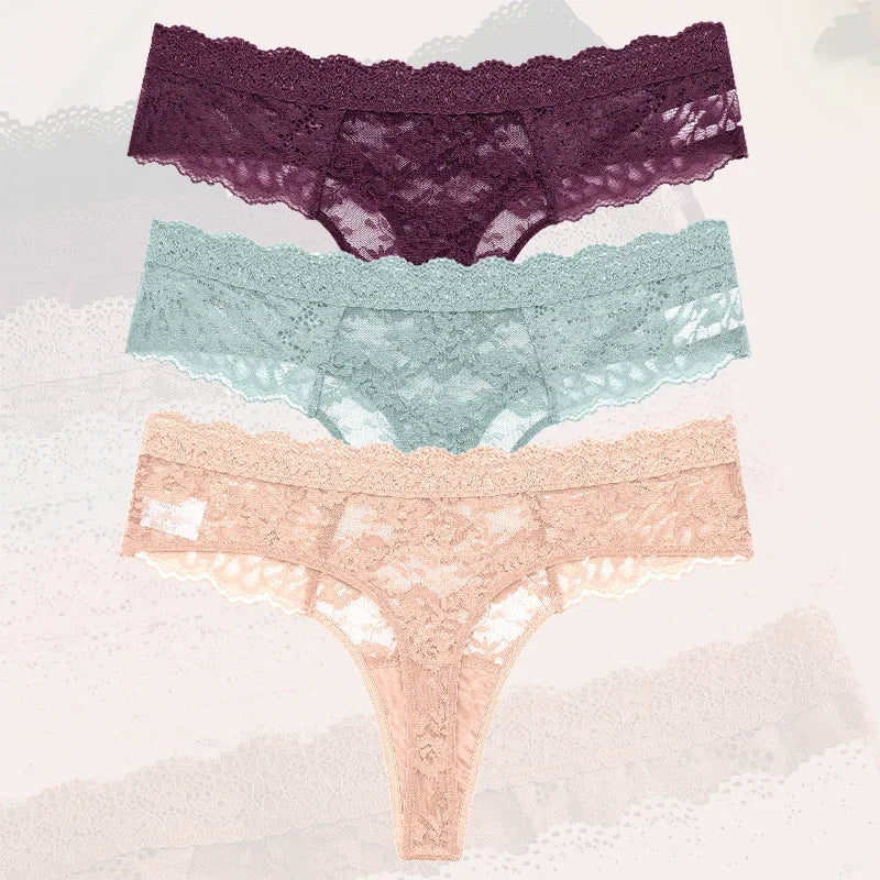 Three pairs of lace underwear in purple, green, and pink on a textured white background.