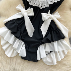 Black swimsuit with white ruffles and bows on a beige surface