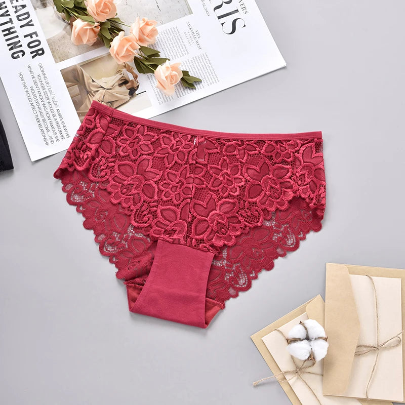 Red lace underwear on a gray surface with flowers and a magazine.