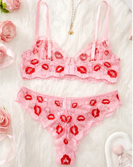Pink lace lingerie set with red lip prints on a white background