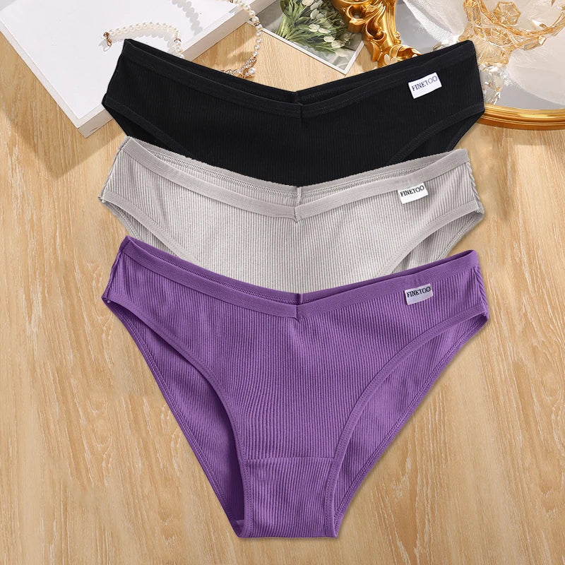 Three pairs of underwear in black, gray, and purple on a wooden surface.