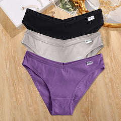 Three pairs of underwear in black, gray, and purple on a wooden surface.