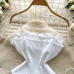 White dress on a wooden hanger against a light background with flowers.